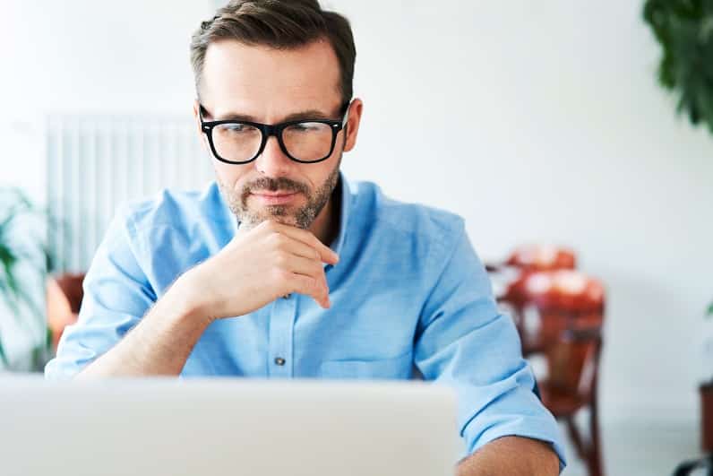 Datenschutz im Unternehmen: Mann mit Brille arbeitet konzentriert am Laptop in einem hellen Büro