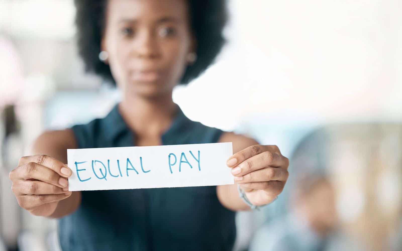 Frau hält Schild mit der Aufschrift Equal Pay als Statement für Lohngerechtigkeit